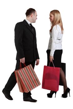 Image of a woman and a man with shopping bags passing by themselves and looking to each other face.