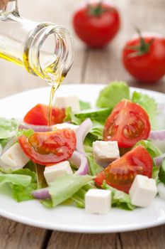 oil pouring over fresh salad 