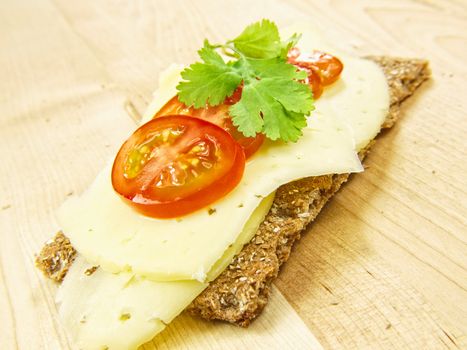 Cracker isolated on wooden plate, with cheese, tomato and parsley