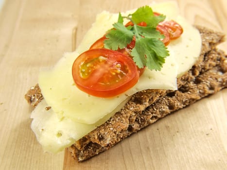 Cracker isolated on wooden plate, with cheese, tomato and parsley