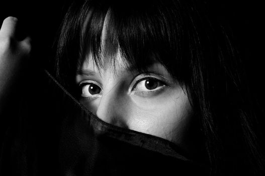 Young arabic girl hiding her face with a scarf in black and white