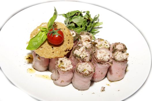 meat rolls with herbs on a plate on a white background