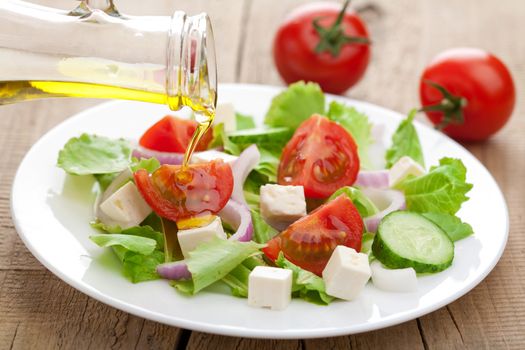 oil pouring over fresh salad 