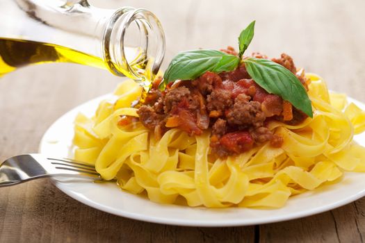 pouring oil over tagliatelle bolognese