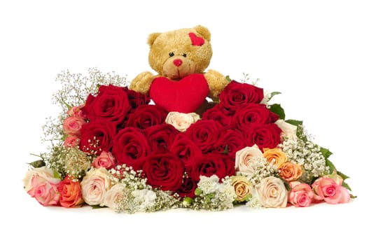 Bouquet of rose flowers isolated on white background. The roses are aranged as a heart shape. A teddy bear is sitting ontop of the flowers.