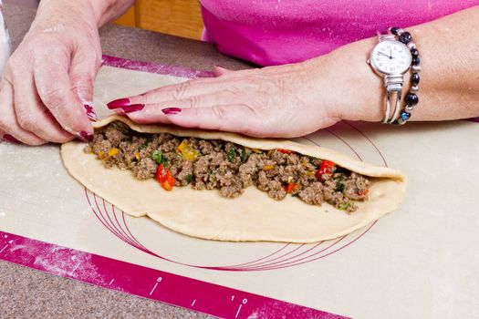 Experienced Hands are wrapping Turkish traditional food Pide with seasoned ground beef.