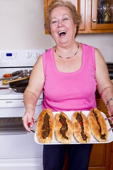 Happy older lady showing freshly cooked Turkish Pides proudly after take them out from the Owen.