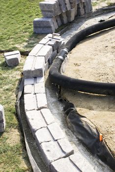 Patio wall base on gravel with corrugated pipe.