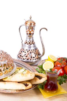 Made with cheese and seasoned ground beef Turkish pide garnished with lemon parsley and tomatoes on the vine. Served with tea and in copper plate.