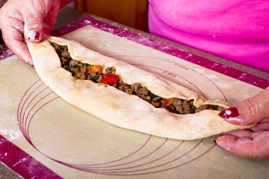 Turkish Pide pocket filled with ground beef roasted peppers, tomatoes, parsley and seasoning getting ready to go to oven.