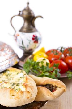 Made with cheese and seasoned ground beef Turkish pide garnished with lemon parsley and tomatoes on the vine. Served with ayran ibrik, and copper plate.