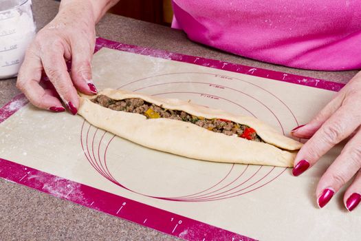 Older lady hands are wrapping Turkish Pide pockets.