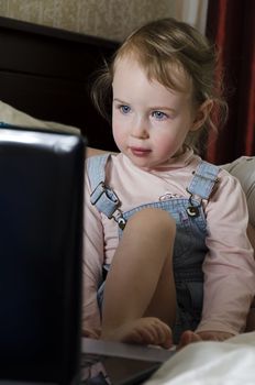 Little girl looks cartoon on the laptop