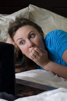 Young woman scared while watching movie in dark room