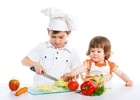 Two smiling kids mixing salad, isolated on white