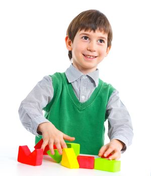 A smiling little boy is building a toy block. Isolated on white background