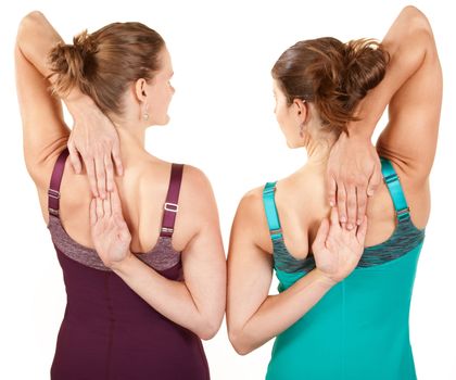 Two fit women stretching their arms over white background