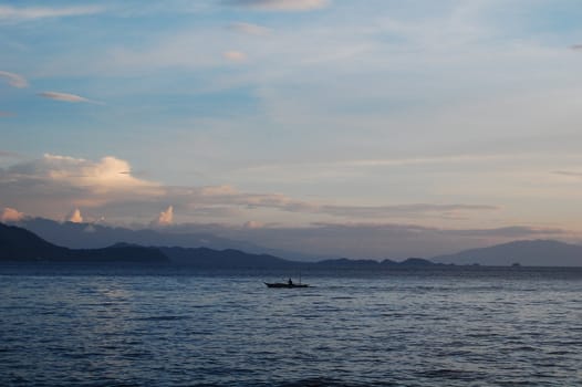 lone fisherman at sea at sunset