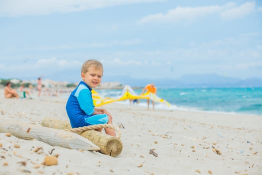 Cute 2 years old boy looking at kiting on tropical beach