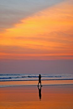Man walking on beach talking on cell phone. Seminyak, Bali, Indonesia.