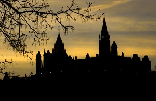 The canadian Parliament bathed in a yellow and blue sunrise glow.