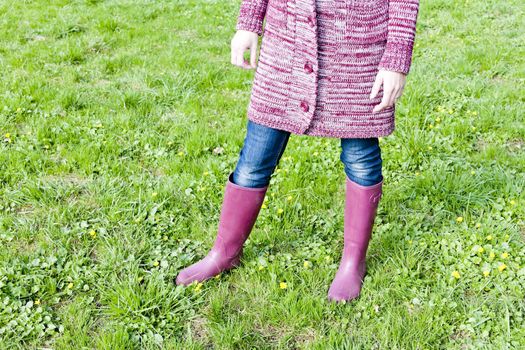 detail of woman wearing rubber boots on spring meadow