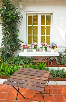 Decorated flowers on window with table and chair in garden