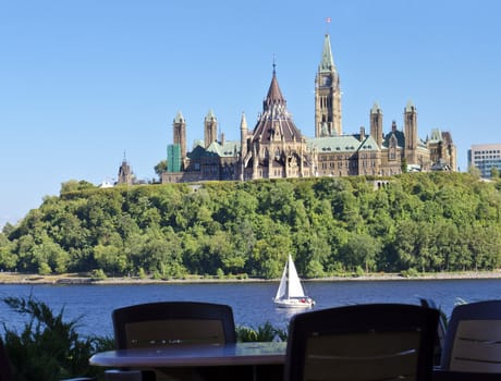 The Canadian Parliament with sailboat on the river.