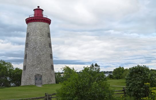 Country stone lighthouse surrounded by greenery.