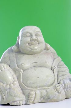 A smiling buddha figurine against a green background.