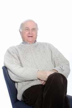 Happy senior man relaxing in a chair with his hands folded on his stomach, isolated on white