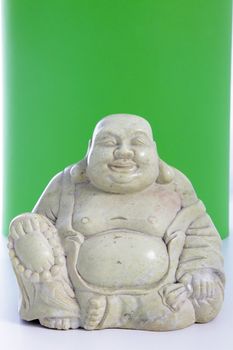 A smiling buddha figurine against a green background.