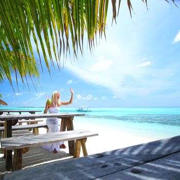 woman sitting in a tropical cafe on the background of a  palm trees and sky and sea