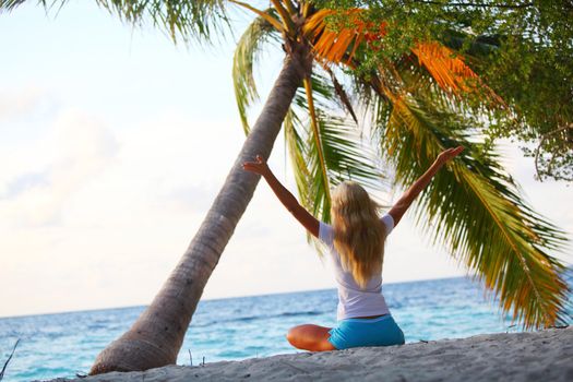 yoga woman on sea coast under palm