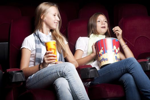 Two girls sitting in a movie theater and watch a movie