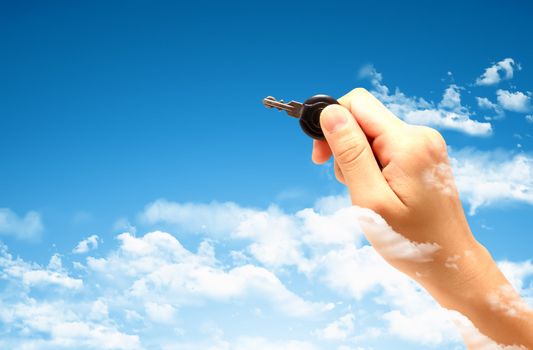 Woman's hand holding key with pretty sky background