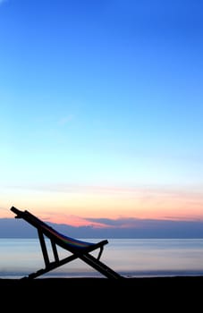 one deckchairs on beach at sunset