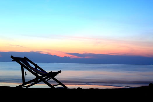 one deckchairs on beach at sunset