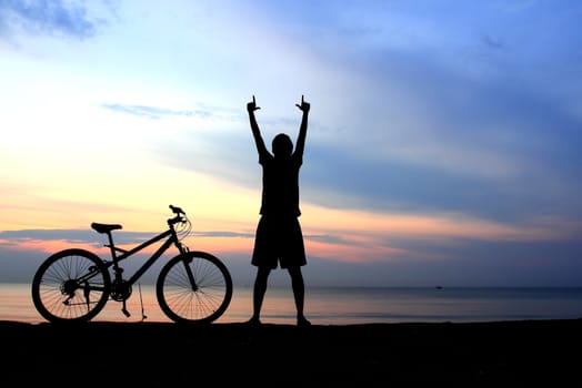 Silhouette of man riding bicycle with beautiful lake near by at sunset