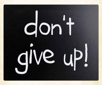 "Don't give up" handwritten with white chalk on a blackboard