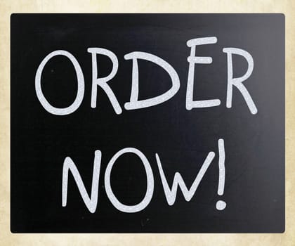 "Order now" handwritten with white chalk on a blackboard