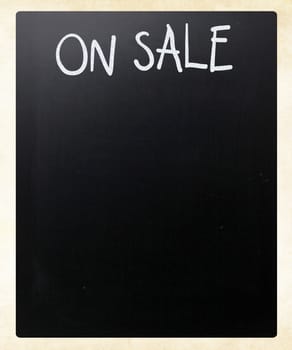 "On sale" handwritten with white chalk on a blackboard