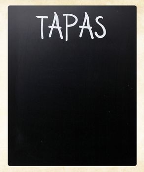 "Tapas" handwritten with white chalk on a blackboard