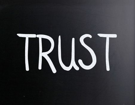 The word "Trust" handwritten with white chalk on a blackboard