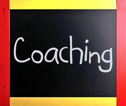 "Coaching" handwritten with white chalk on a blackboard