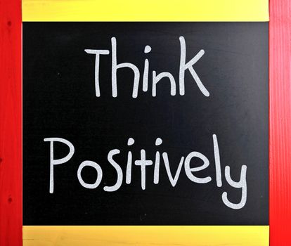 "Think Positively" handwritten with white chalk on a blackboard