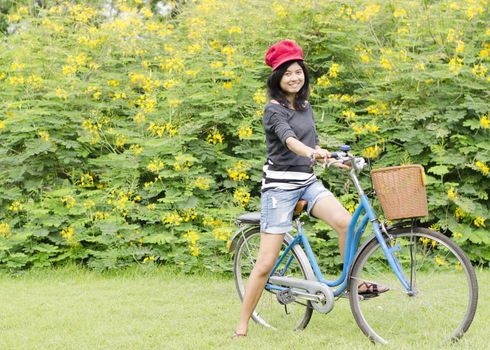 Happy young woman on a green meadow with a bicycle 