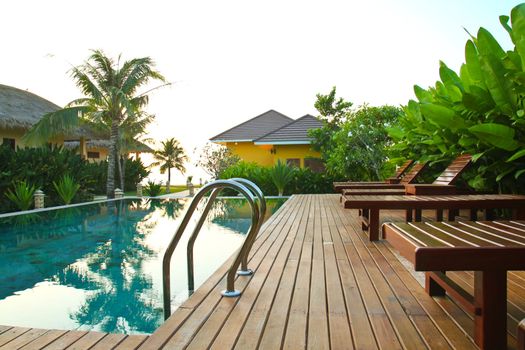chair and swimming pool surrounded by  tropical plants