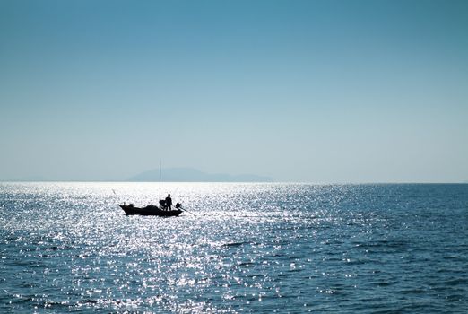 The silhouette of a fisherman with his boat in the sea