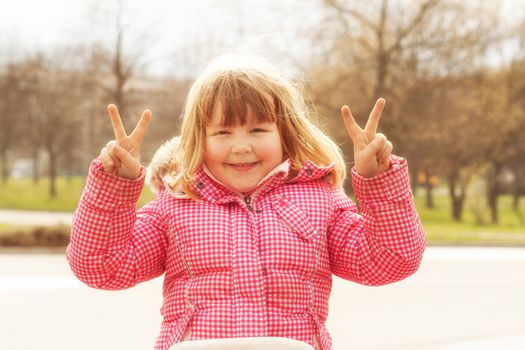 Happy little Girl is showing the victory hand sign